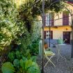 Giardino con piante rigogliose e tavolino - Charming House Bice